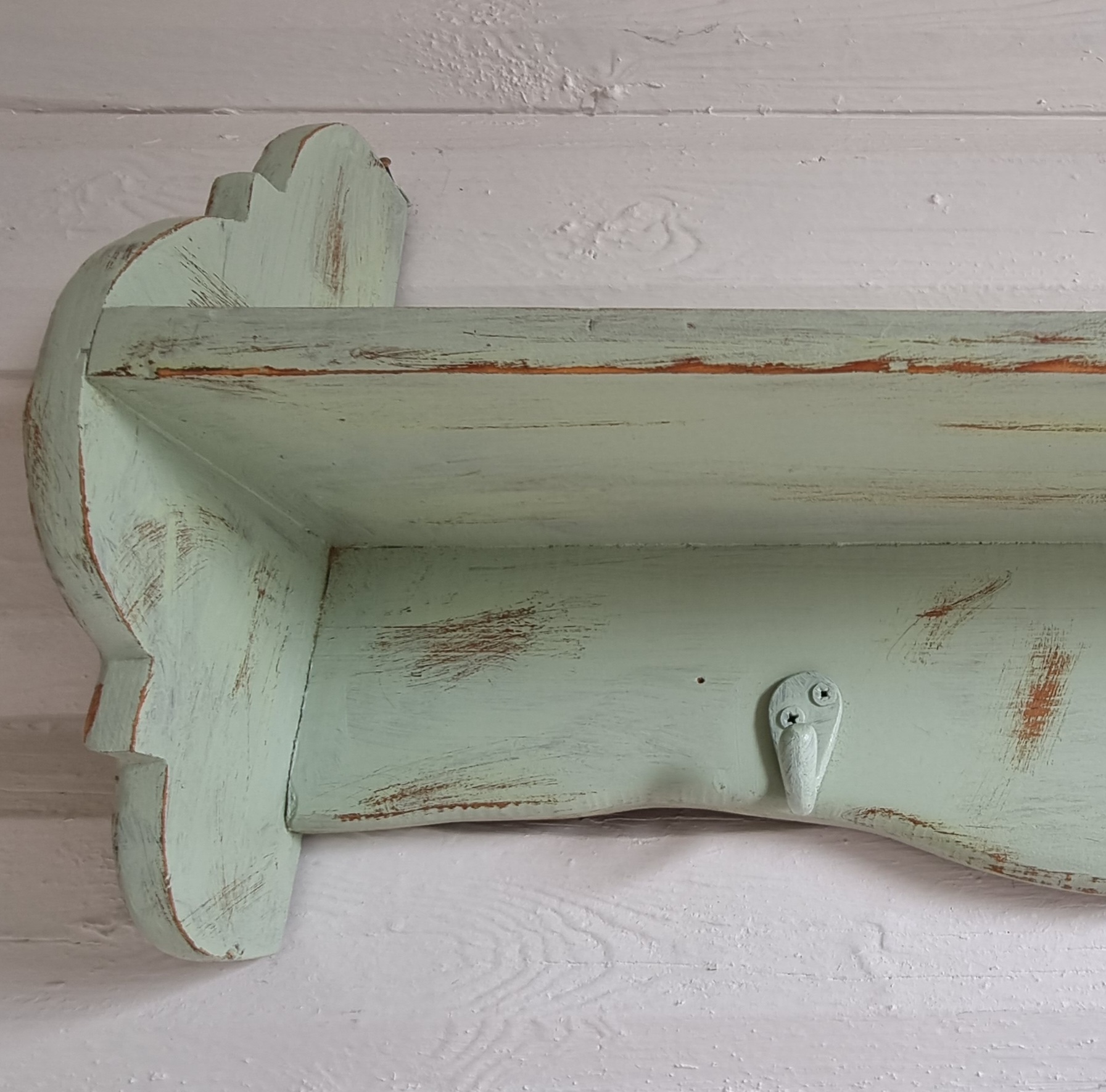 Pastelgrøn hylde med knager