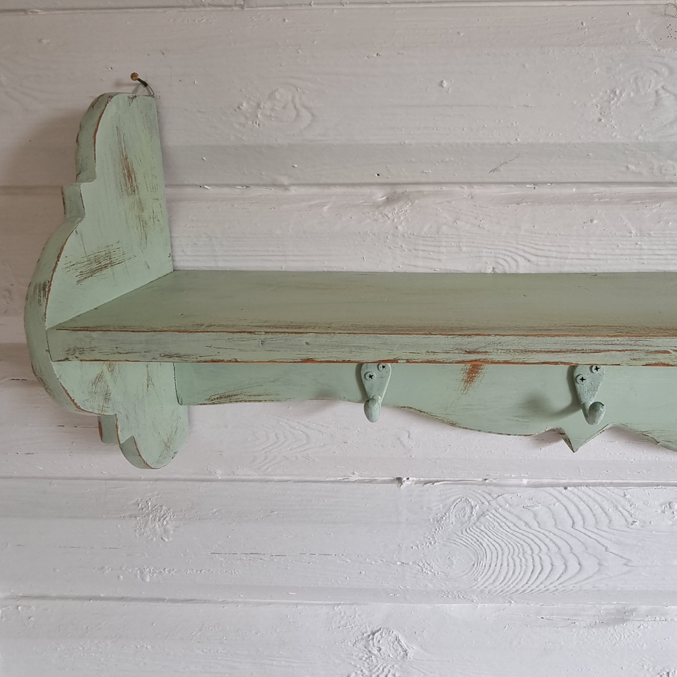 Pastelgrøn hylde med knager